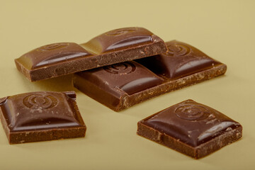 Close-up of a broken chocolate bar on a neutral background showcasing rich textures