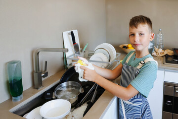 Smiling Boy Washing Dishes at Kitchen Sink with Foam