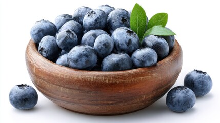 Abundance of blueberries fill a wooden bowl, two leaves are seen amongst the fresh fruit.