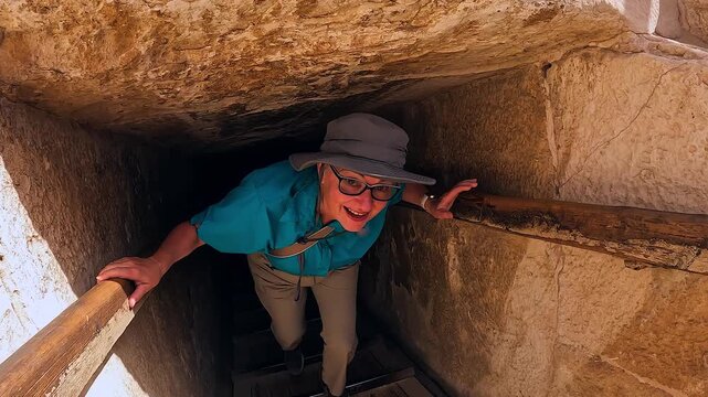Female tourist emerges from small passage to underground Egyptian tomb