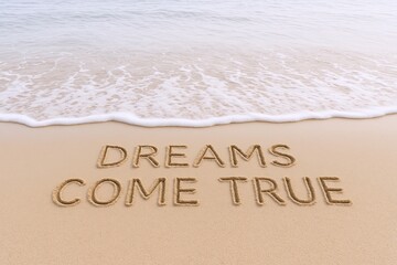 Motivational Quote "Dreams Come True" Written in Sand on Beach Shoreline.