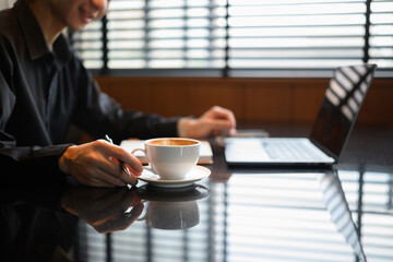 Close-up of a hand holding a coffee cup and laptop during a casual work session, Work and Coffee...