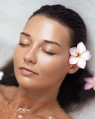 Relaxed Woman With Glowing Skin And Flower In Hair Lying In Bath