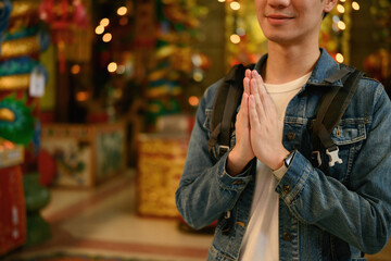 Visiting a colorful Chinese temple, a close-up image of a tourist respectfully greets with a serene...
