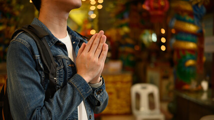 Close-up of a traveler's hands folded in prayer, a backpacker pays respect during a cultural visit...