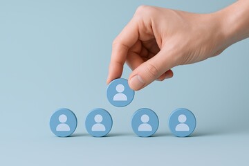 Hand placing a human icon on a row of four blue profile icons representing teamwork and collaboration.