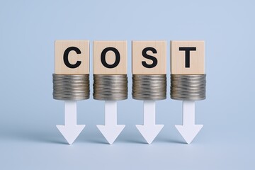 Visual representation of decreasing expenses using wooden blocks spelling COST supported by stacked coins with downward arrows on a light blue background.