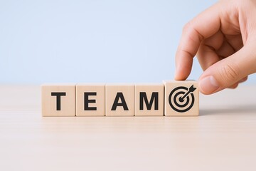 Hand arranging wooden blocks spelling TEAM with target symbol for collaboration.