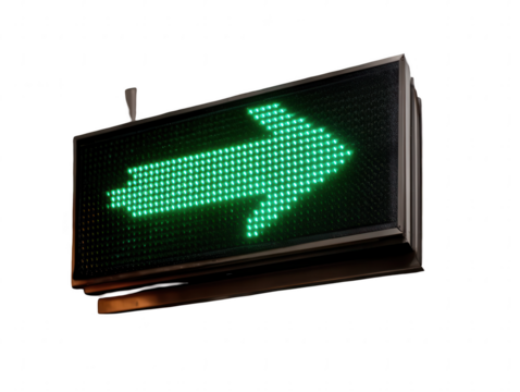 Illuminated green arrow sign pointing right against a black background in a close up shot
