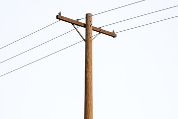 Wooden Utility Pole with Power Lines Standing Vertically against a White Background.