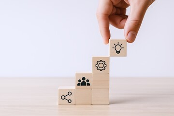 Hand placing wooden block with light bulb icon above gear icon on stacked wooden steps.