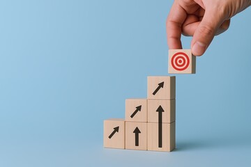Hand stacking wooden blocks with upward arrows and target symbol on a light blue background.