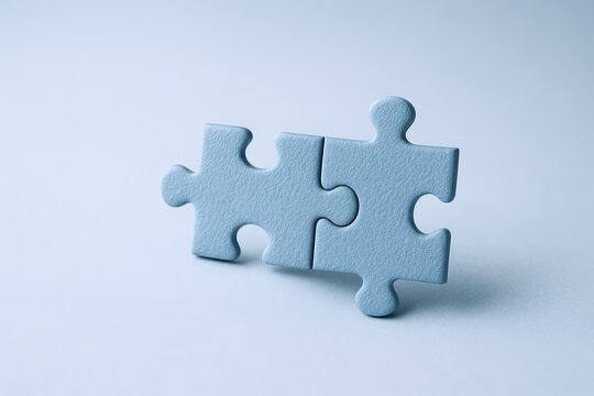 Close-up of two light blue puzzle pieces fitting together on a plain background.