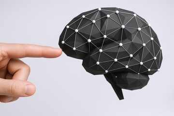 Human finger touching a geometric wireframe brain model representing artificial intelligence.