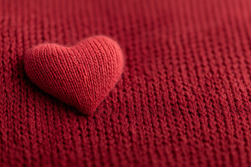 Fototapeta premium A close-up shows a knitted heart on knitted cloth. The texture of yarn creates warmth and romance, making it perfect for heartfelt messages.