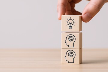 Hand stacking wooden blocks with light bulb and gear icons symbolizing ideas and innovation.