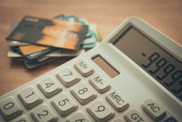 White calculator shows minus delinquent and many credit cards on wooden table background. Credit card debt loan, personal financial problem, bank high interest rate, bankruptcy and so on concept.