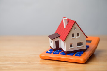 Home and calculator on wooden table with white wall background copy space. Home finance, expenses, mortgage loan, buying or rental house, money savings management planning, refinance and so on concept