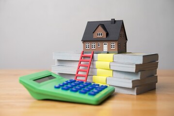 House model, red ladder, stack banknotes and calculator on wooden table white wall background. Home finance, expenses, spending money, financial planning, mortgage loan, homebuyer and so on concept.
