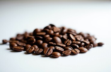 Obraz premium Coffee beans scattered on a white surface creating a simple and clean composition