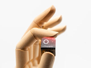 Mano de madera sujetando un dado con varios símbolos de  de la tabla de elementos químicos