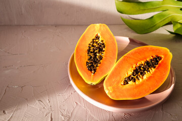 Halved Ripe Papaya with Tropical Leaf on Light Background