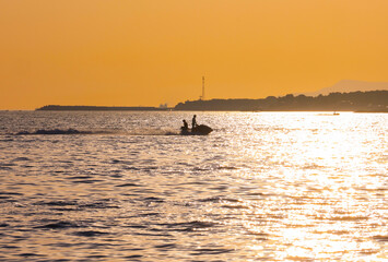 Jet ski racing across the sea during a beautiful sunset on a summer evening. Silhouettes