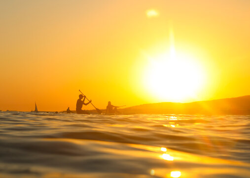 young people  riding  on sup surfing in the sea at sunset.