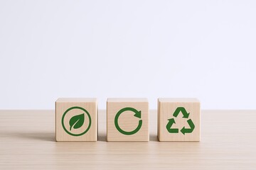 Eco friendly recycling concept with wooden blocks displaying leaf cycle and recycling symbols.