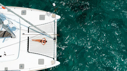 Slender woman on a yacht. Beautiful white woman sunbathing on the bow of a snow-white sailing yacht...