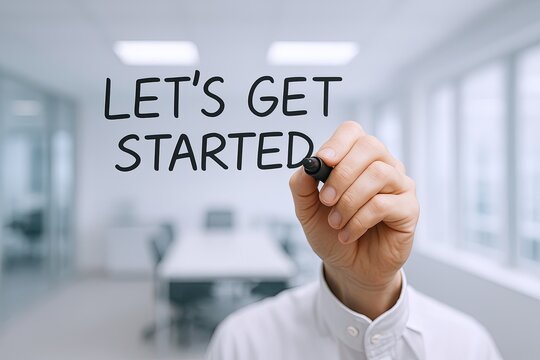 Handwriting marker drawing phrase Let's Get Started on transparent glass wall in modern office.