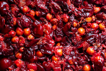 Red cherry pits and pulp after squeezing out the juice as a background, closeup. Texture of cherry...