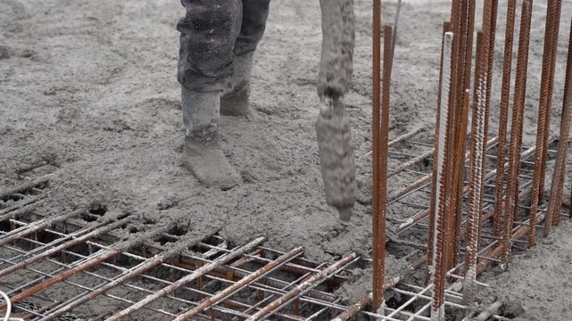 Construction Worker Pouring Fresh Concrete on Reinforced Slab