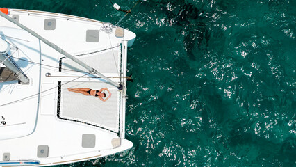 Slender woman on a yacht. Beautiful white woman sunbathing on the bow of a snow-white sailing yacht...