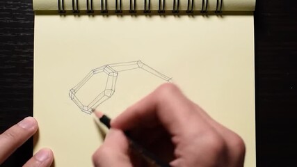 Hand drawing geometric shapes on yellow paper with pencil