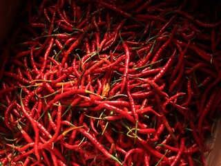 Fototapeta premium Curly red chilies at a traditional market. A background of spicy and fresh red chilies. A common ingredient in Asian cuisine.