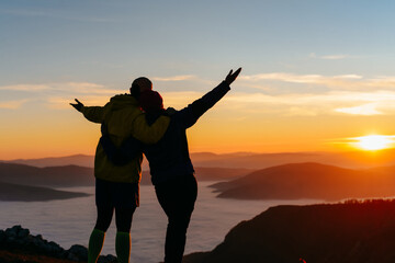 Couple embracing and enjoying sunrise on mountain © Minet