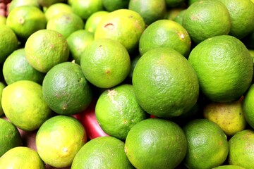 A close-up photo of a bunch of fresh green limes. These citrus fruits have a sour and refreshing taste, and can be added to food or drinks.