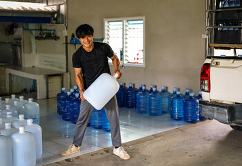 male warehouse worker lifting a Gallon drinking water, Workers transfer drinking water bottles from...