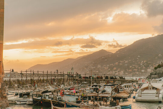 Boats docked in harbor at sunset with mountains in background