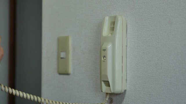 A close-up view of a vintage intercom system mounted on a wall.