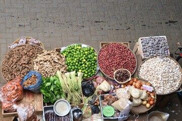 A vendor selling aromatic cooking spices such as key limes, garlic, ginger, turmeric, and cloves at a traditional market. Fresh and flavorful ingredients commonly used in Asian cuisine.