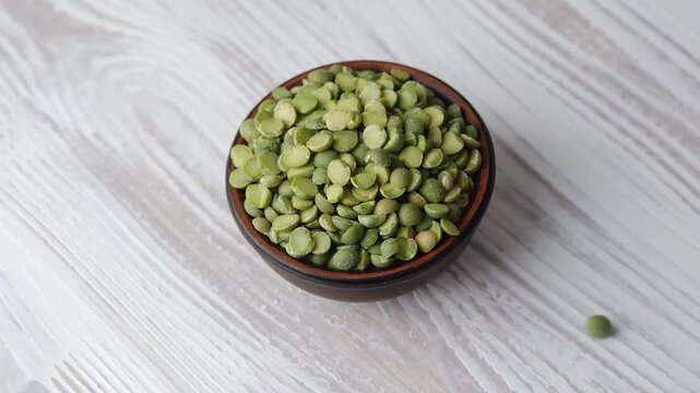 wooden bowl with green split peas on white table background for healthy eating and kitchen concept