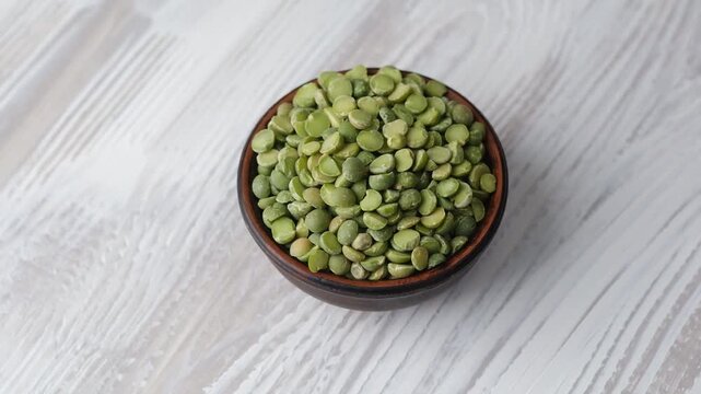wooden bowl with green split peas on white table background for healthy eating and kitchen concept