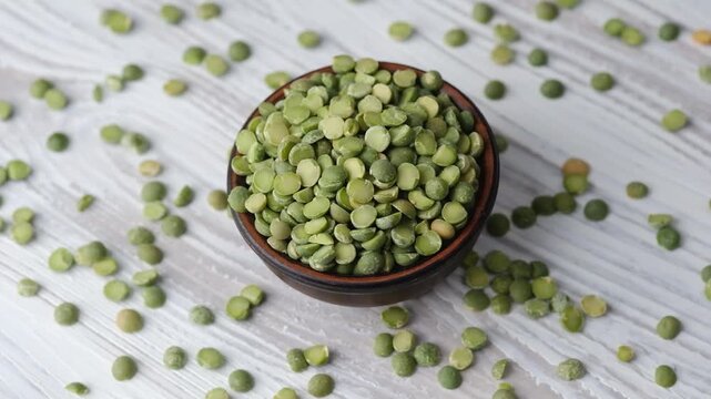 wooden bowl with green split peas on white table background for healthy eating and kitchen concept