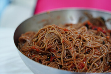 Close-Up of Korean Buckwheat Noodles with Spicy Sauce and Vegetables in Metal Bowl