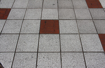 Texture of square paving tile. Pattern of gray and red sidewalk tiles in the street. Concrete pavers close up background.