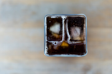 Selective focus of iced americano in square shape glass. Top view