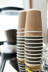 The stack of brown and black cups stacked upside down on the coffee machine at the coffee shop,...