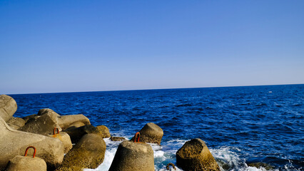 ゴツゴツしたテトラポットに波が迫り来る